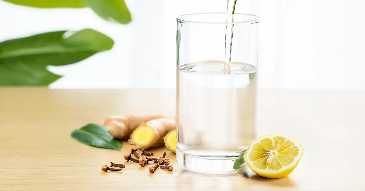 glass of water with cleansing herbs beside it